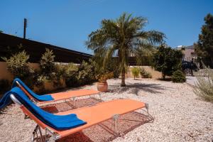 Dos sillas de playa y una mesa y una palmera. en Diana's Heights by Prestige Bookings, en Peyia