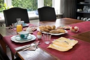 a wooden table with a breakfast of eggs and bread at B&B Villa Kriekenbeek in Lent