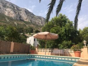 ein Pool mit einem Regenschirm und einem Berg im Hintergrund in der Unterkunft Villa Marta - Montgó in Denia