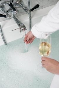 a person holding a glass of wine under a sink at Riga Suites Antwerp in Antwerp