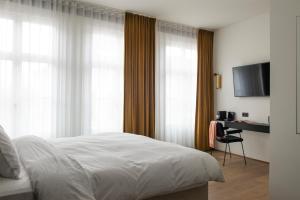 a bedroom with a bed and a desk with a television at Riga Suites Antwerp in Antwerp