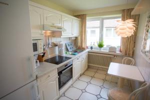 a kitchen with white cabinets and a sink and a window at Ferienwohnanlage Dünenhaus in Hohwacht