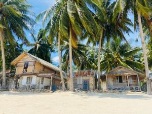 an old house on the beach with palm trees at Castaway Beach Bungalows in Srithanu