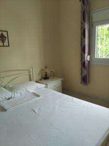 ein weißes Bett in einem Schlafzimmer mit Fenster in der Unterkunft ASTERIA HOUSE in Kala Nera