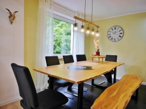 une table à manger avec des chaises et une horloge murale dans l'établissement Die HAMMERHÜTTE, à Willingen