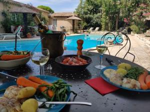 a table with plates of food and a bottle of wine at Gites Climatisés Piscine Chauffée La Balancelle in Saint-Rémy-de-Provence