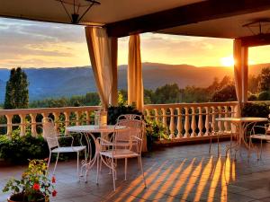 a patio with tables and chairs on a balcony with the sunset at Hospedium Hotel Val de Pinares in Bogarra