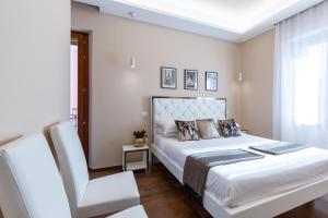een witte slaapkamer met een bed en een stoel bij Club 57 Imperial Rooms in Cagliari