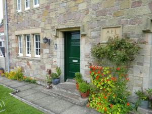 eine grüne Tür auf einem Steinhaus mit Blumen in der Unterkunft Ford Village Bed & Breakfast in Ford