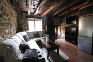 a living room with a white couch and a tv at El Salto del Agua in Orbaneja del Castillo