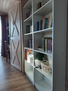 a white book shelf with books and a door at Domek na drzewie in Trześcianka