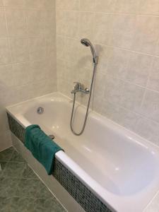 eine Badewanne mit Dusche und ein grünes Handtuch in der Unterkunft Apartmán V hájích Malá Skála in Malá Skála