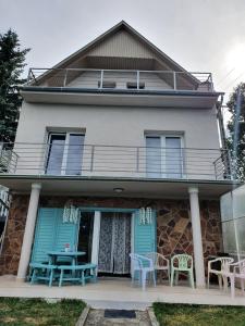 ein Haus mit blauen Türen sowie einem Tisch und Stühlen in der Unterkunft Mama motel in Zánka