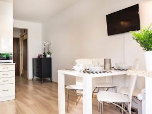 biała kuchnia z białym stołem i krzesłami w obiekcie VacationClub – Zdrojowa 22 Apartament 5 w Świnoujściu