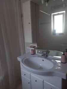 Un baño con un lavabo blanco y un espejo. en Big apartment next to Olympus mountain, en Litóchoron