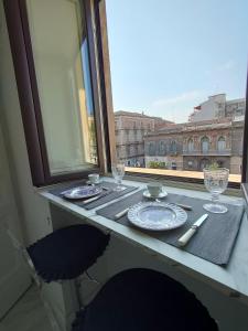 einen Tisch mit Tellern und Gläsern an einem Fenster in der Unterkunft Finestre in piazza in Catania