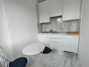 eine kleine weiße Küche mit einem Tisch und Stühlen in der Unterkunft Finestre in piazza in Catania