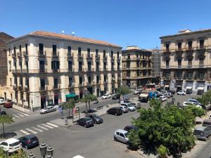 eine Stadtstraße mit Autos, die vor den Gebäuden geparkt sind in der Unterkunft Finestre in piazza in Catania