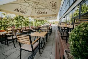 una fila de mesas y sillas con sombrillas en un patio en University Hotel Dorrah en Tuzla