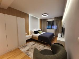 a bedroom with a bed and a tv and a chair at Shell Sky Luxury Penthouse with Private Pool in Zadar +52 photos