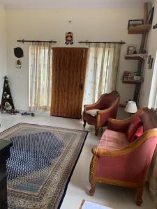 a living room with two chairs and a rug at Narayana Lake Hide Out in Bhīm Tāl