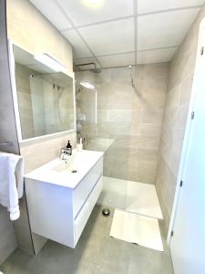 La salle de bains est pourvue d'un lavabo blanc et d'une douche. dans l'établissement La Manga Principe Relax Ferienwohnung am Strand mit exklusiver Ausstattung, à Los Narejos