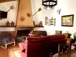 sala de estar con sofá rojo y chimenea en Casa Rural El Poleo, en Villaviciosa de Córdoba