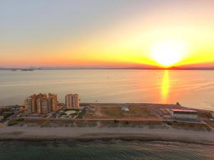 - une vue aérienne sur la ville et l'océan au coucher du soleil dans l'établissement La Manga Principe Relax Ferienwohnung am Strand mit exklusiver Ausstattung, à Los Narejos