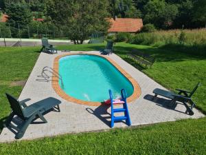 a swimming pool with two lawn chairs and a toy ladder at Penzion Kamzík in Česká Kamenice