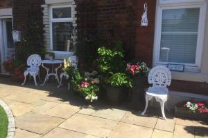 two white chairs and a table and some flowers at Leafy Lytham central Lovely ground floor 1 bedroom apartment with private garden In Lytham dog friendly in Lytham St Annes