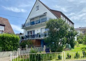une maison blanche avec une clôture devant dans l'établissement Helle moderne Ferienwohnung, Nähe Koblenz am Rhein, à Weitersburg