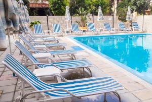 a row of lounge chairs next to a swimming pool at San Remo Hotel in Larnaka