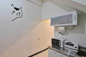 a kitchen with a microwave and a cat on the wall at 鹿鹿咪民宿 in Lukang