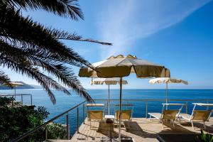 a balcony with chairs and an umbrella and the ocean at Excelsior Palace Portofino Coast in Rapallo