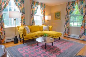 a living room with a yellow couch and a table at Sally Webster Inn in Rockport