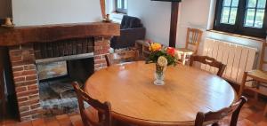 una mesa de madera con un jarrón de flores encima de una chimenea en Gite à la ferme, en La Ferté-Saint-Samson