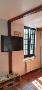 a living room with a large flat screen tv on the wall at Gite à la ferme in La Ferté-Saint-Samson