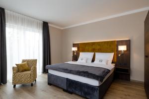 um quarto com uma cama grande e uma cadeira em Herzl Hotel bei Erding em Forstern