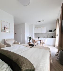 a white bedroom with a large bed and a table at Royal Sand Apartment in Gdańsk