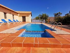 uma piscina com cadeiras e uma casa em Magic house em La Oliva