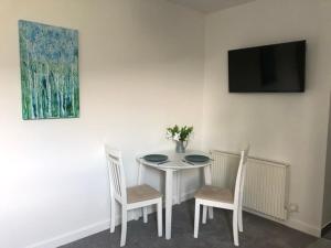 a white table with two chairs and a tv on a wall at Flat 2 Frank Lewis House in Hay-on-Wye