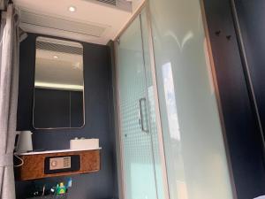 uma casa de banho com um espelho e uma cabina de duche em vidro. em SnapNap em Storabø
