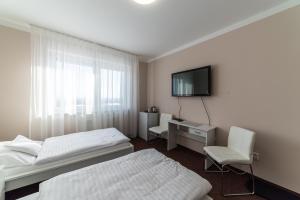 1 dormitorio con 2 camas, escritorio y TV en Penzion Lomská Vyhlídka, en Lom u Mostu