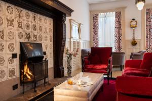 a living room with a fireplace and red chairs at Hotel Engiadina in Zuoz