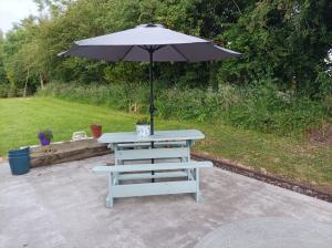 una mesa de picnic con una sombrilla y un banco en Country Lane Homestay, en Westport