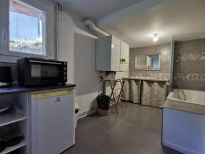 a small kitchen with a microwave and a window at Villardy in Châtillon-sur-Chalaronne