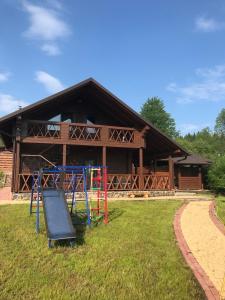 um parque infantil em frente a uma cabana de madeira em ЕкоСадиба Пан Атаман em Skhidnitsa