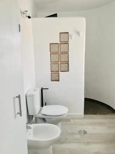a white bathroom with a toilet and a sink at Azzurro house in El Cotillo
