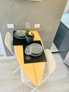 a yellow table with plates and glasses on it at Azzurro house in Cotillo