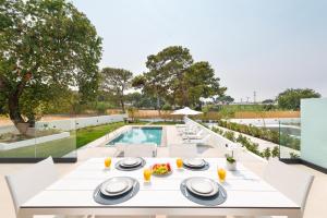 an outdoor dining area with a table and chairs and a pool at Aurum Villas in Ialysos